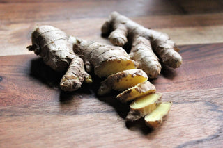 Frisches Ingwer-Rhizom (Zingiberis rhizoma) auf Holzuntergrund, aufgeschnitten