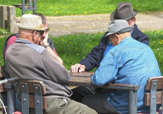 Vier ältere Männer sitzen entspannt im Freien an einem Tisch beisammen