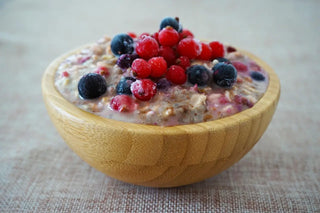 Holzschale mit Porridge und gefrorenen Beeren, ein Frühstück für die tägliche Routine